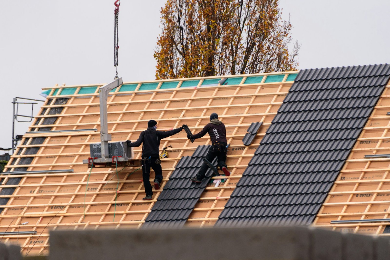 Roofers installing tiles on a new roof